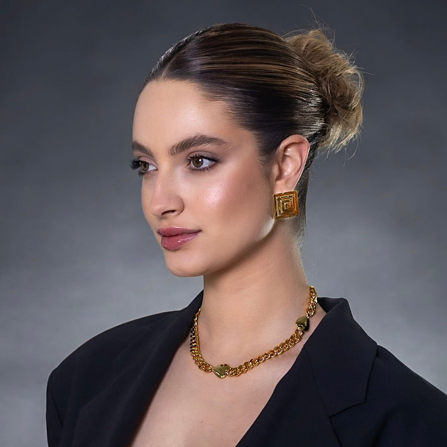 Woman wearing gold jewelry against a gray background