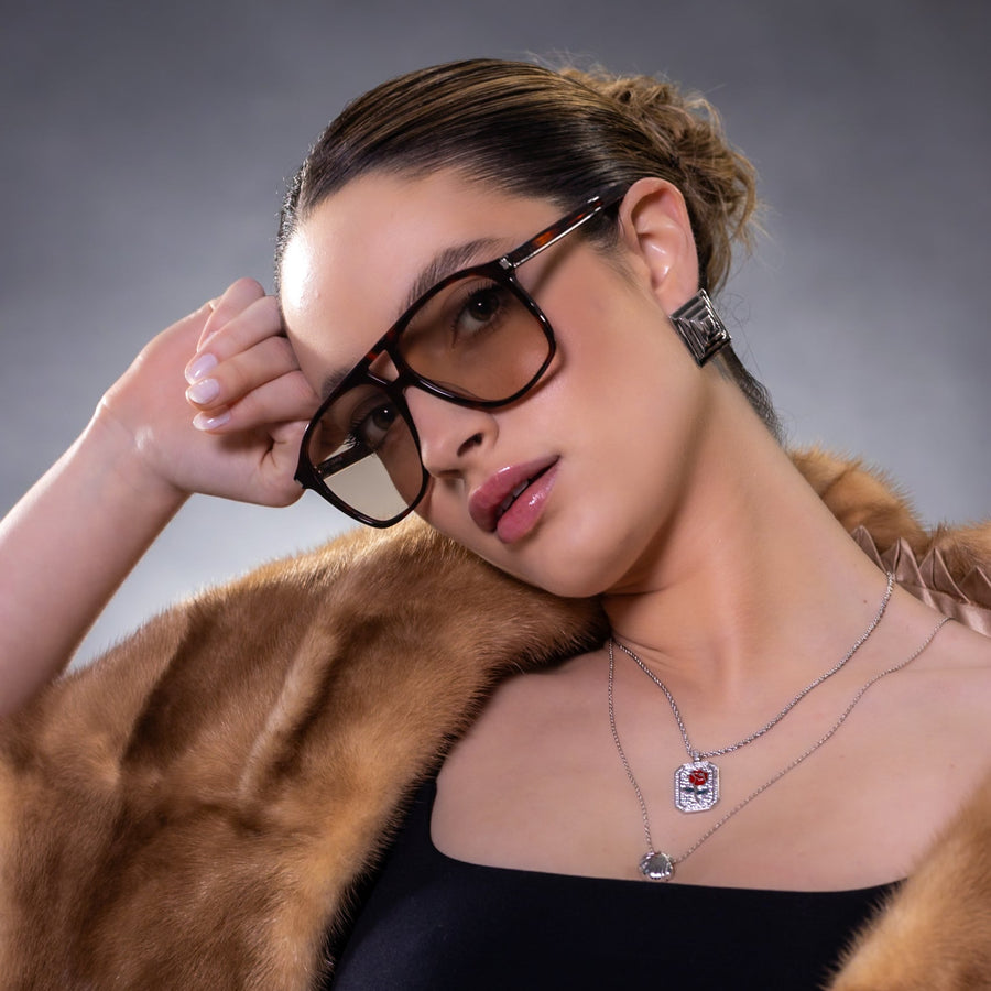 Woman wearing glasses and a fur coat against a gray background